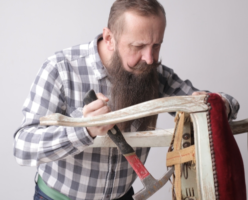 vertical-shot-man-with-long-beard-mustache-fixing-broken-chair_181624-23276